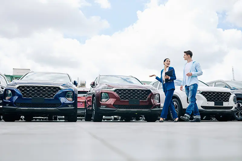 Woman sales person showing young man around a dealership