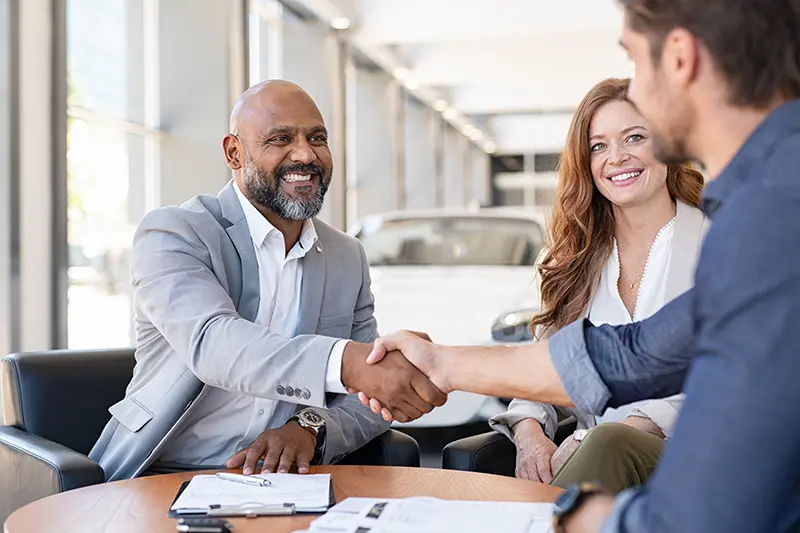 Dealership salesman shaking hands with man who just purchased a vehicle